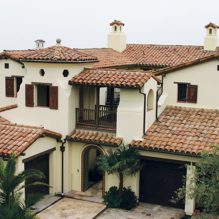 an aerial view of a house with red tile roofs and palm trees in the foreground