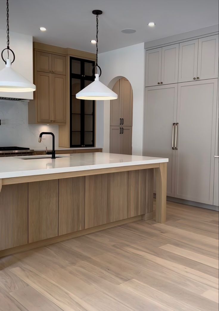 an empty kitchen with two pendant lights hanging from the ceiling