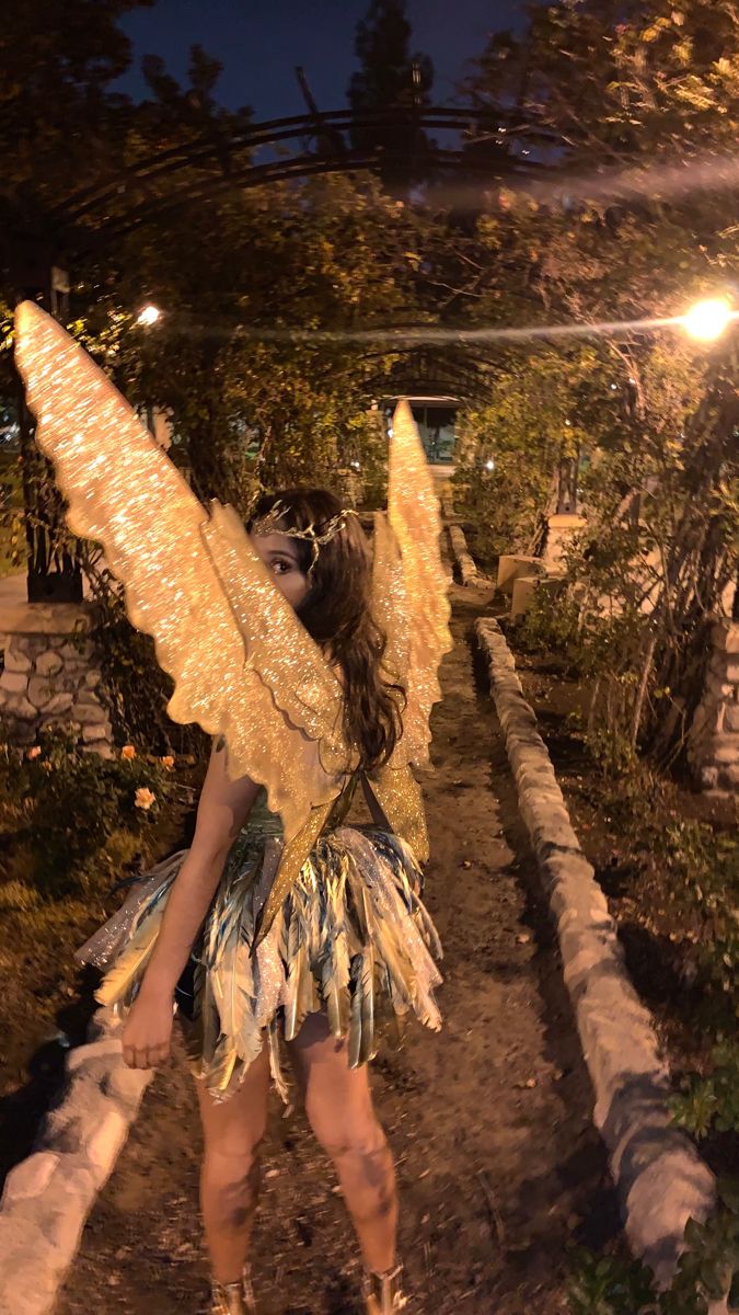 a woman dressed as an angel standing on a path