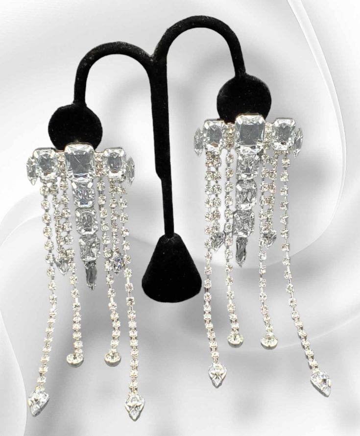 "Dripping with Ice": Dare to dazzle with our "Dripping with Ice" Earrings! These stunning earrings are fully adorned with blingy strands of dripping rhinestones, making you the star of any event. Elevate your style and sparkle with confidence! Approximately 5.5" long, 2 inches in width. Weight: approximately 1.3 ounces for the pair. Party Long Drop Chandelier Earrings, Long Drop Rhinestone Party Jewelry, Party Long Drop Rhinestone Jewelry, Party Jewelry With Rhinestones In Long Drop Shape, Party Jewelry With Long Drop Rhinestones, Dangle Crystal Chandelier Earrings For Party, Silver Crystal Bling Earrings For Party, Silver Bling Crystal Earrings For Party, Sparkling Drop Chandelier Earrings For Party