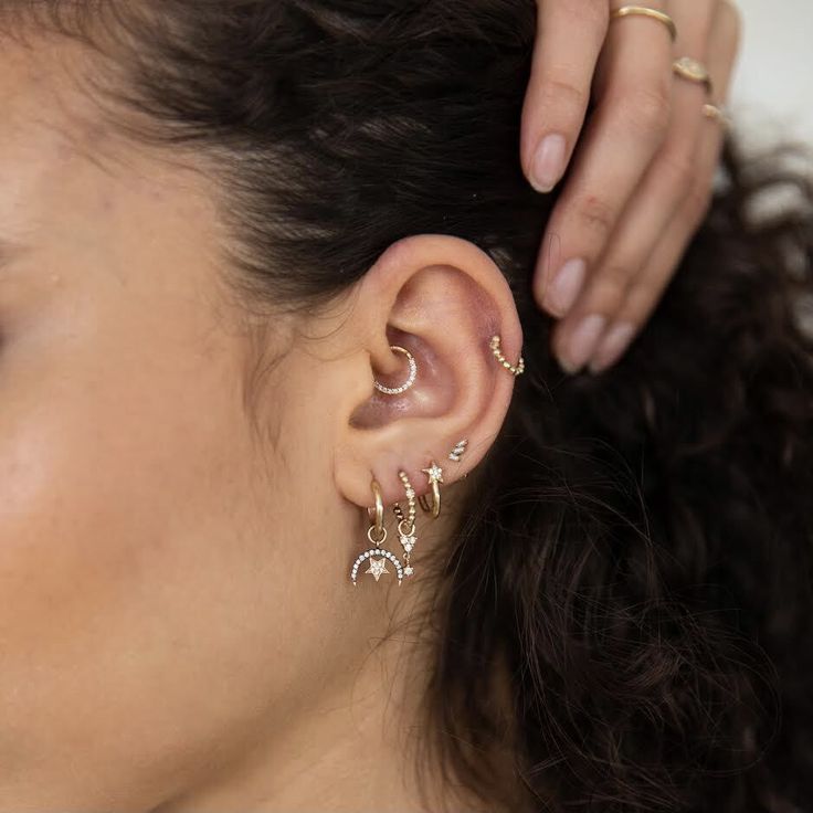 a close up of a person's ear wearing gold and silver earrings with stars on them