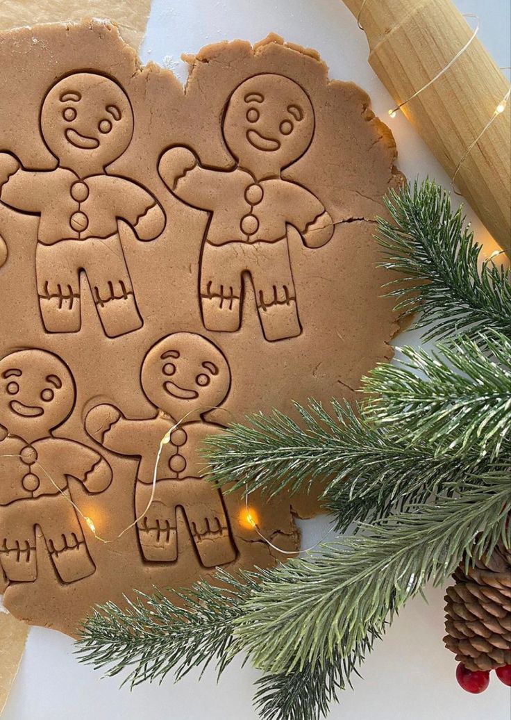 gingerbread cut out with christmas lights and pine cones on the table next to it