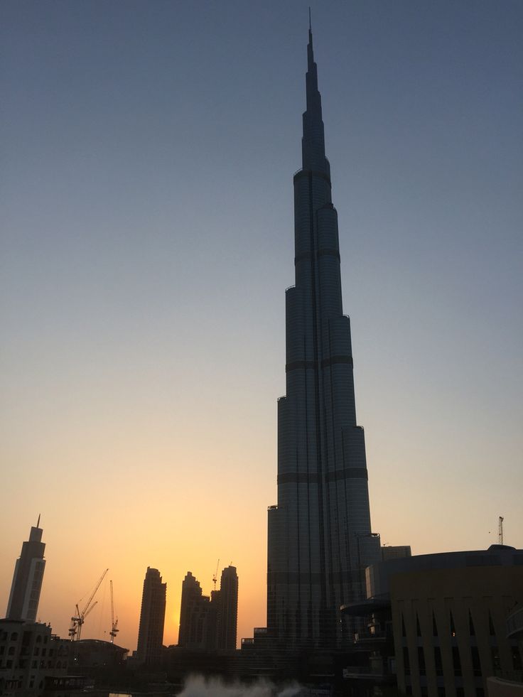 the burj tower is silhouetted against the sunset in the middle of the city