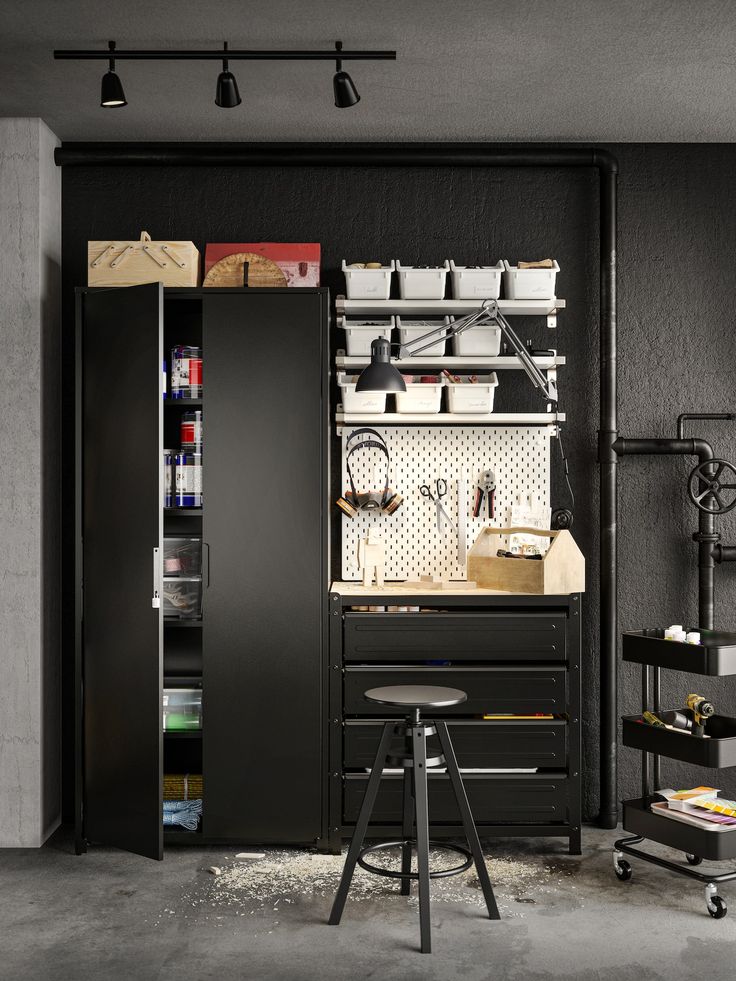 an organized garage with lots of storage and tools in the cabinet door, along with two stools