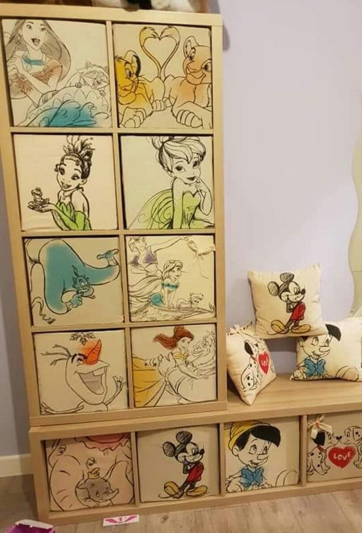 a wooden shelf with many disney characters painted on the front and side panels, along with several pillows