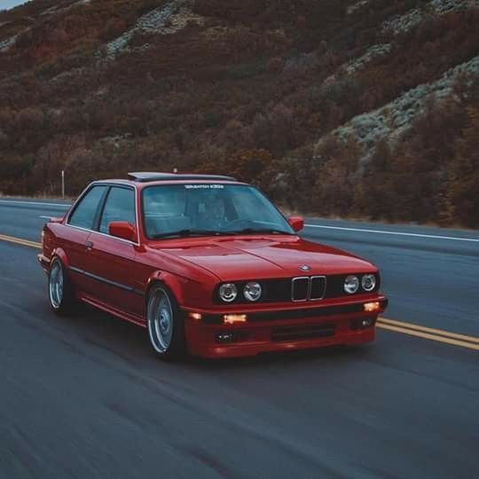 a red bmw is driving down the road