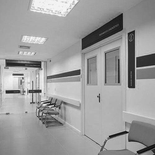 an empty hospital hallway with chairs and signs on the walls, in black and white