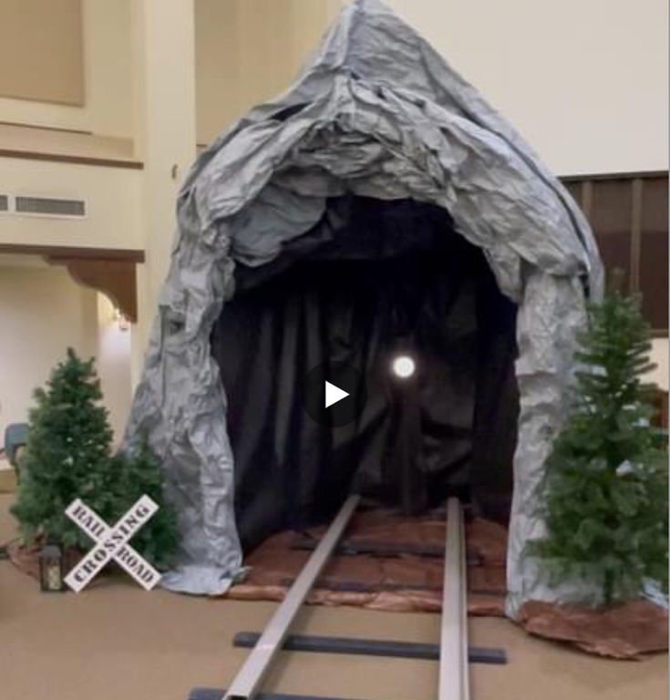 a train track going through a tunnel in the middle of a room with christmas trees