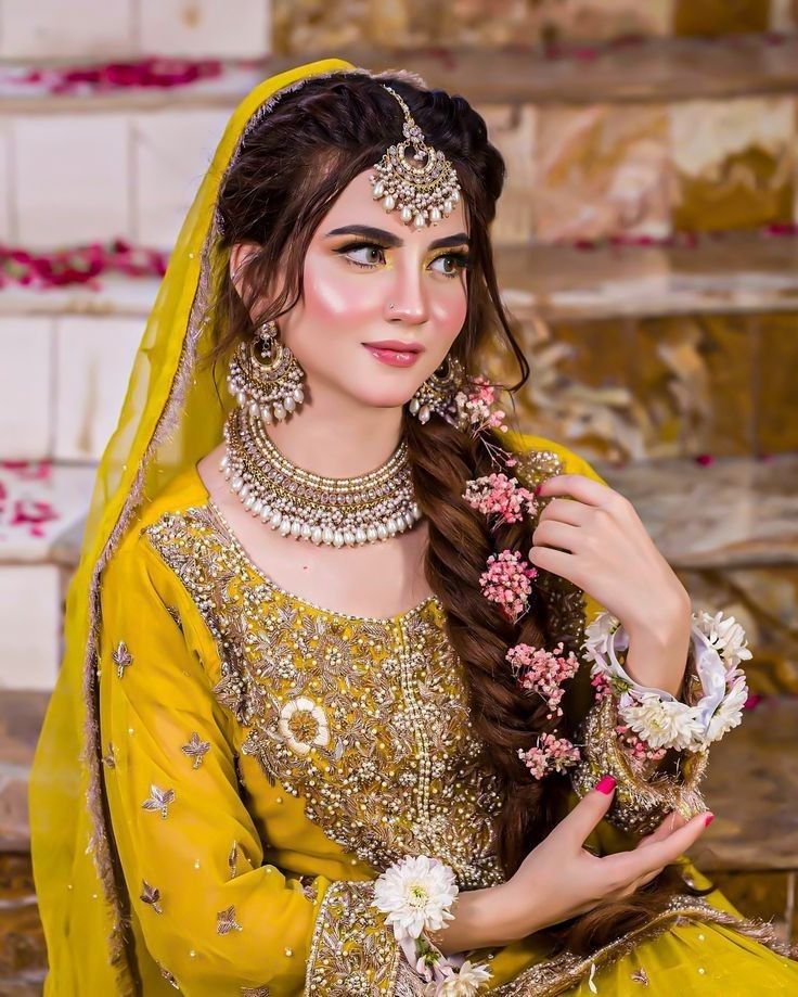 a woman in a yellow bridal outfit with long hair and jewelry on her head