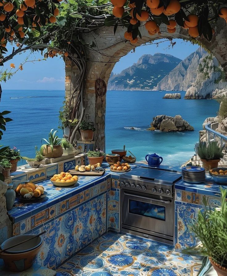 an outdoor kitchen with blue tile and oranges on the counter top, overlooking the ocean