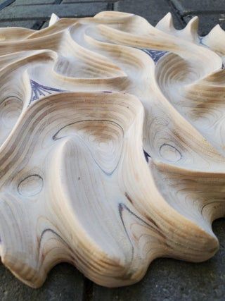 a wooden bowl sitting on top of a sidewalk