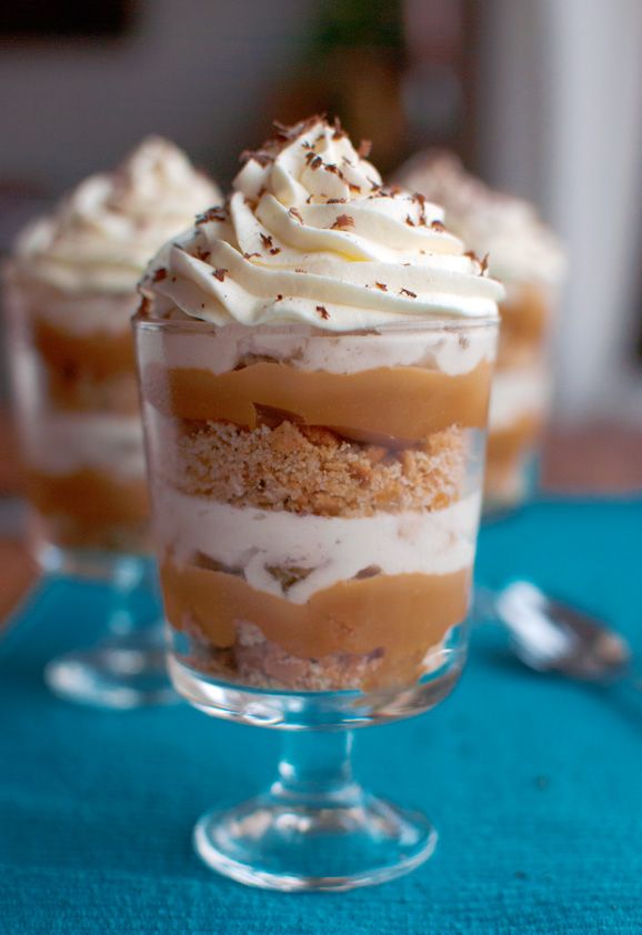 three desserts in small glass dishes on a blue tablecloth with spoons and forks