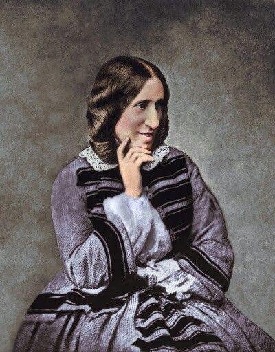 an old photo of a woman in a dress sitting on a chair with her hand to her chin