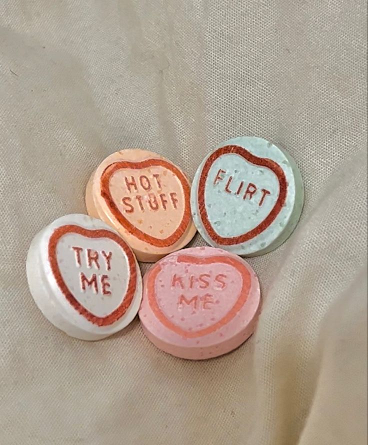 four candy hearts with the words, hot stuff, try me and flirt on them