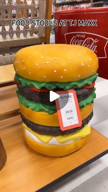 a giant hamburger sitting on top of a wooden table next to a red and white sign