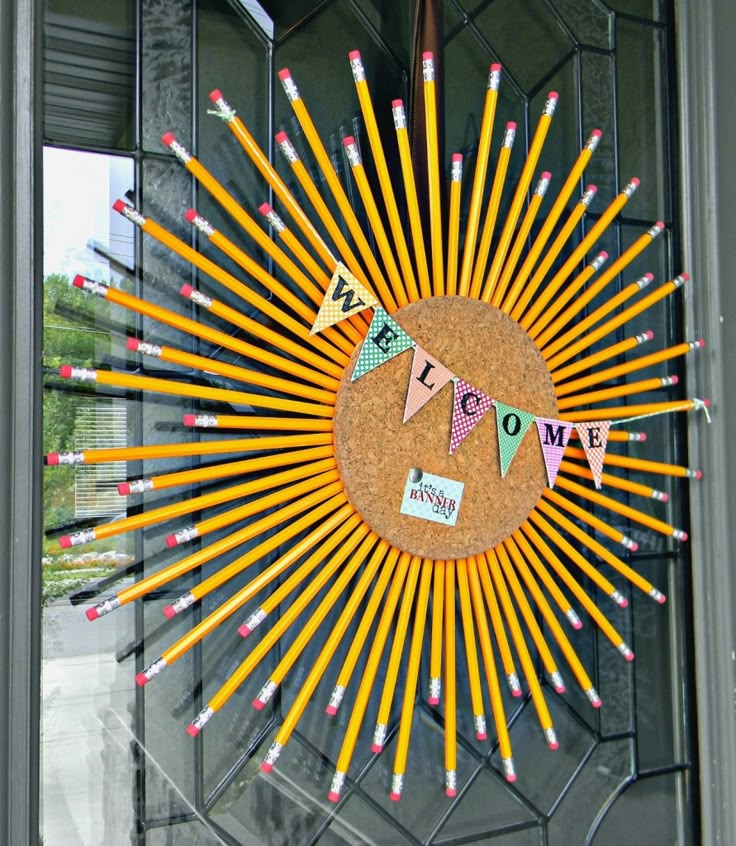 a sunburst made out of pencils is hanging on the front door window