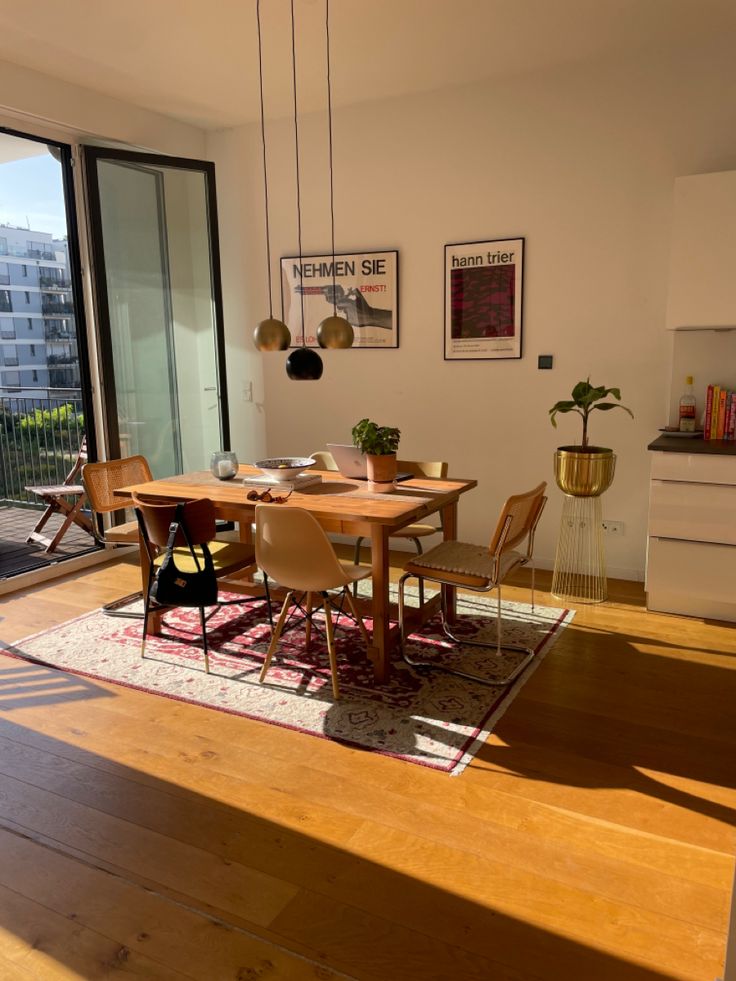 a dining room table with chairs and a rug on the floor in front of a sliding glass door