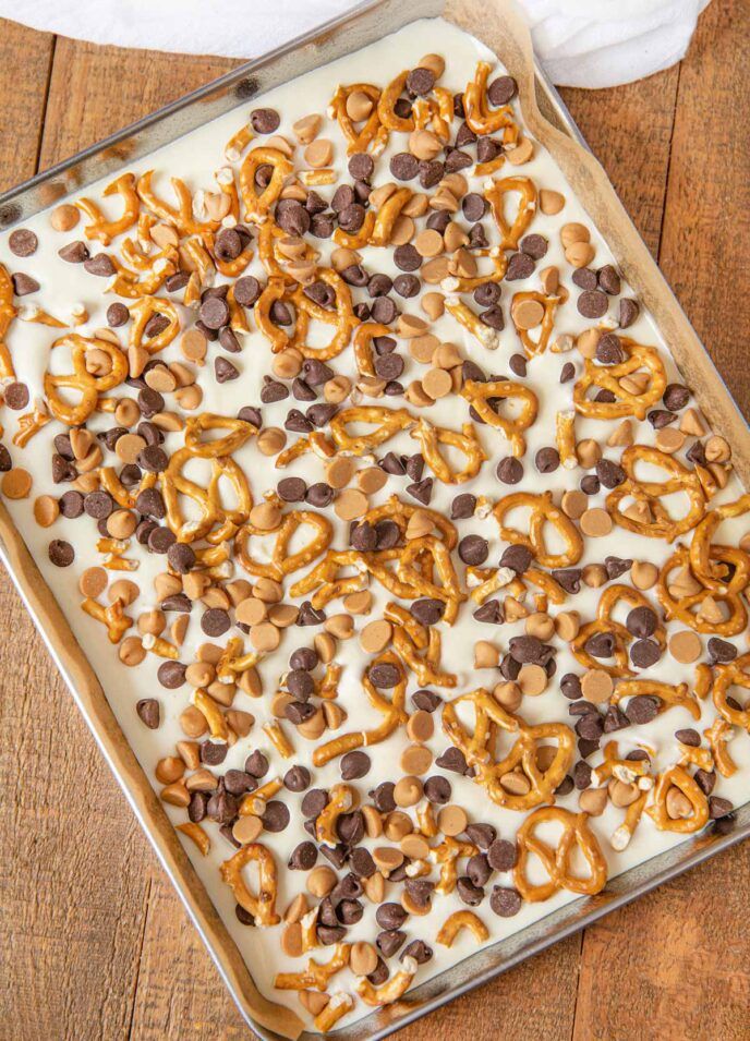 a pan filled with chocolate and pretzels on top of a wooden table