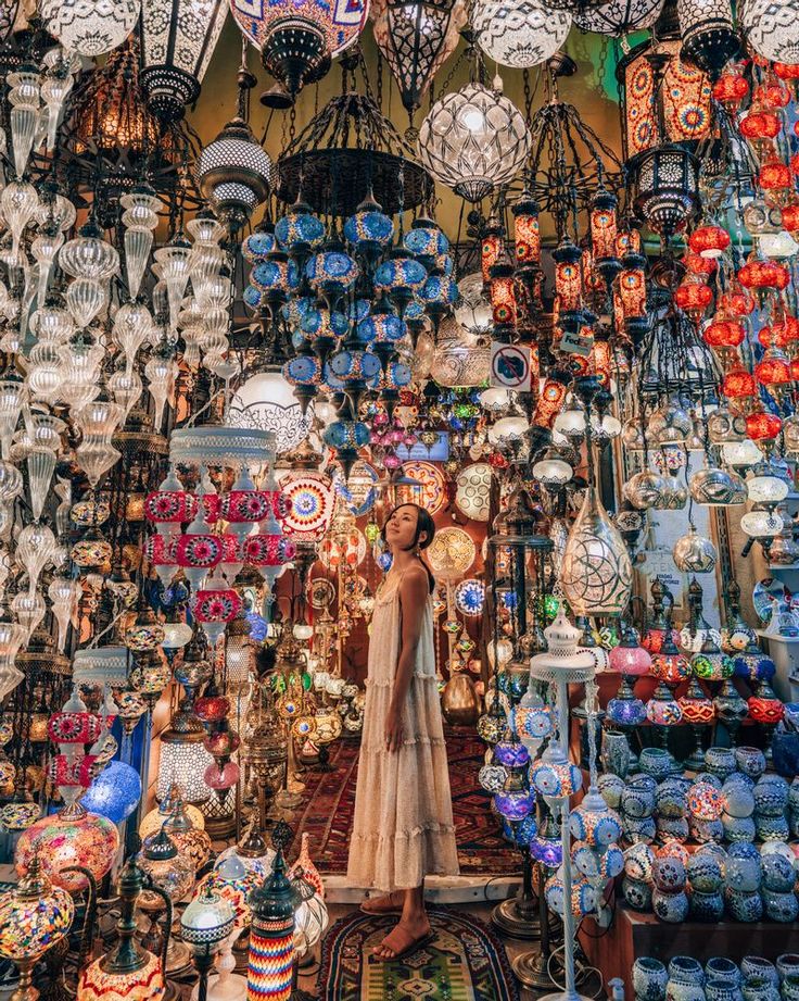 a woman standing in front of a large display of colorful glass lamps and vases