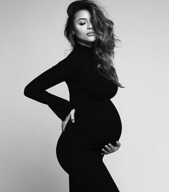 a pregnant woman posing for a black and white photo with her hands on her hips