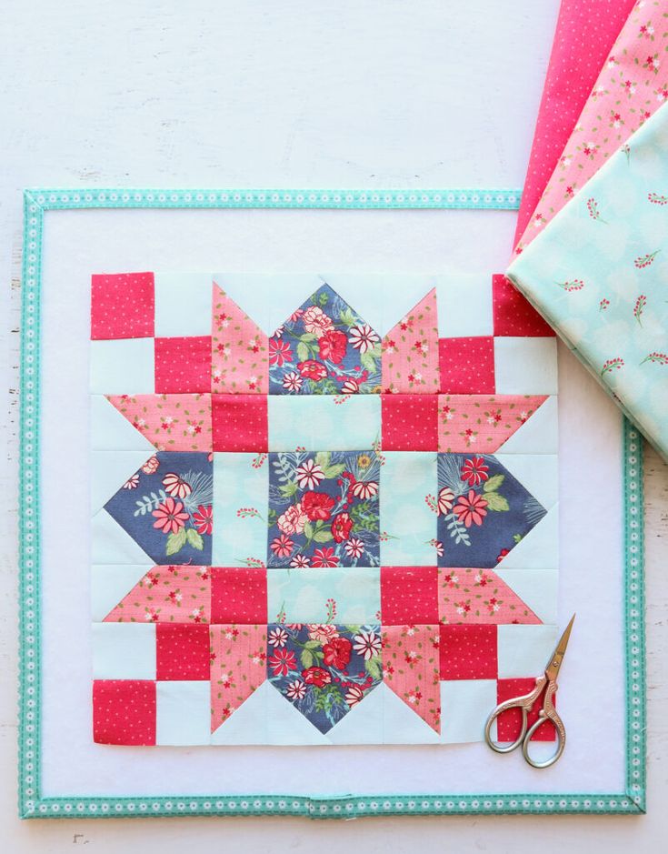 a quilt and scissors on top of a piece of fabric