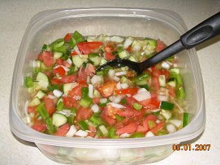 a plastic container filled with lots of veggies and a black spoon in it