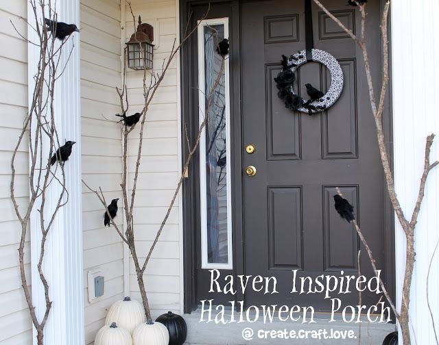 a front door decorated for halloween with black and white pumpkins on the porch, branches and wreath