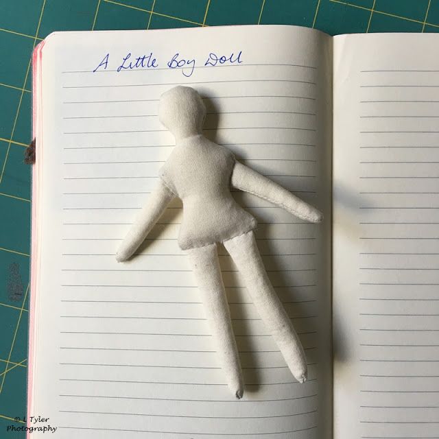 an open book with a stuffed doll laying on top of it next to a pen