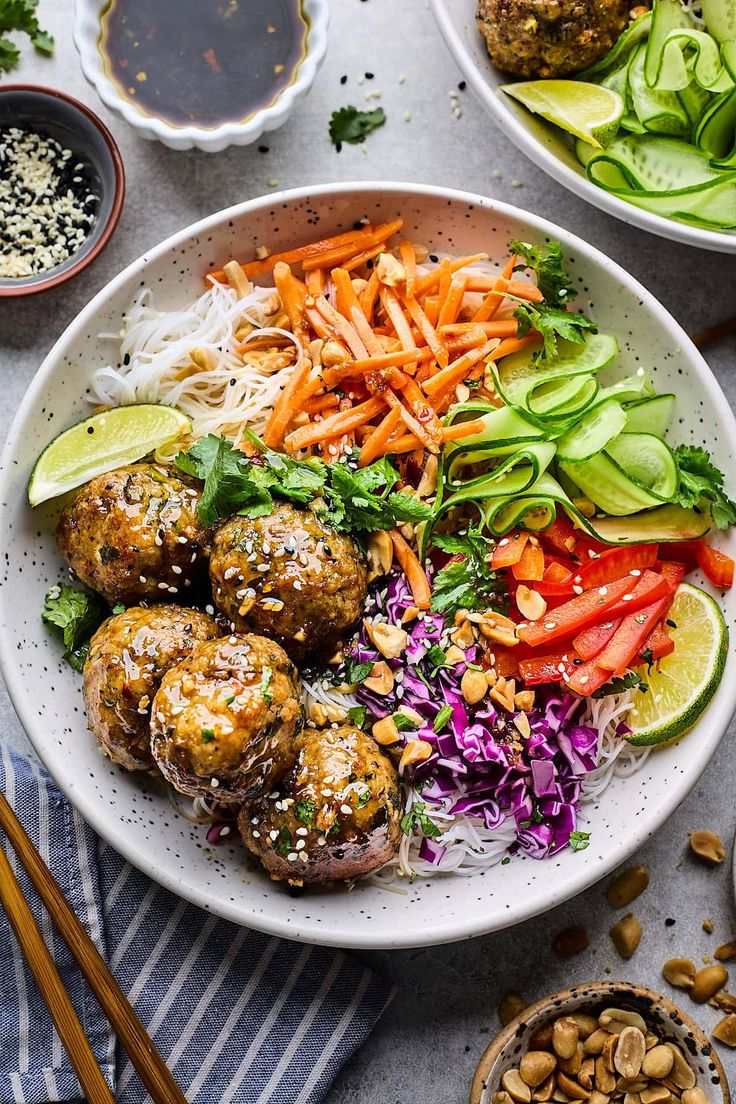 a bowl filled with meatballs and veggies next to bowls of sauces