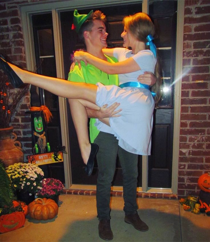 a man holding a woman in his arms while standing next to a door with pumpkins