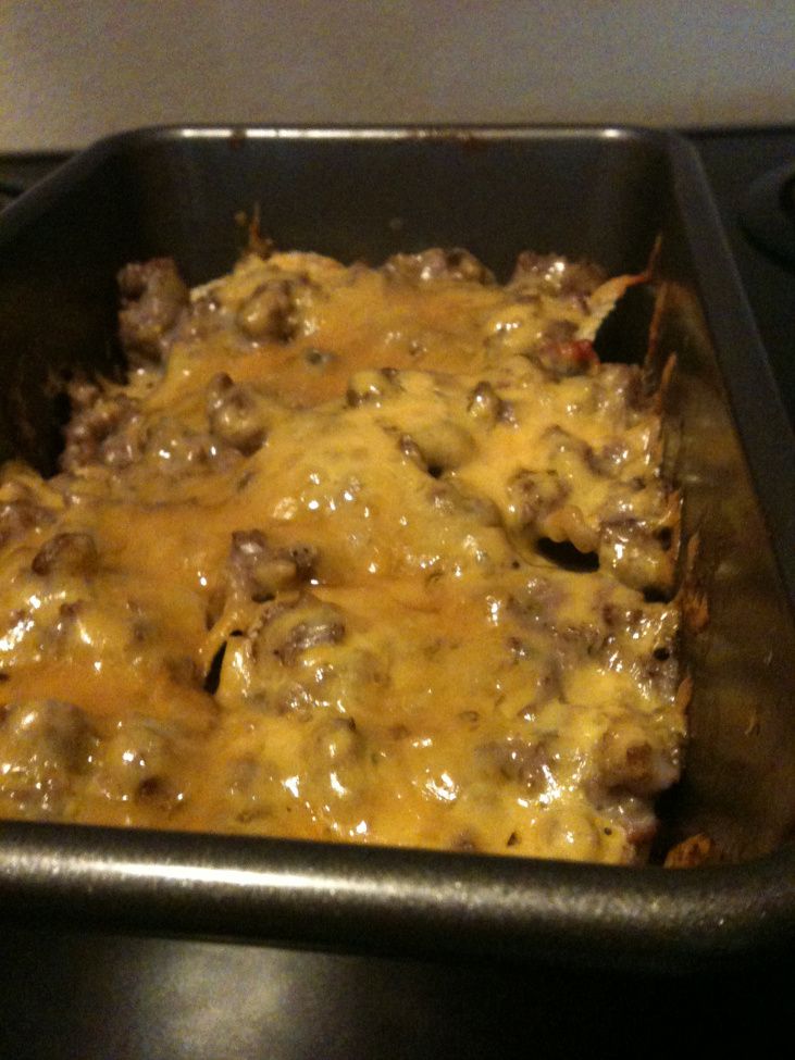 a casserole dish with cheese and meat in it sitting on a stove top