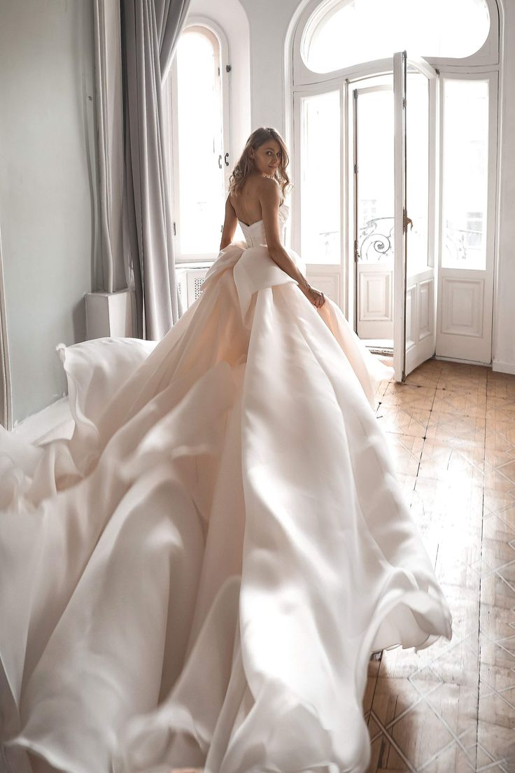 a woman in a wedding dress is sitting on the floor with her back to the camera