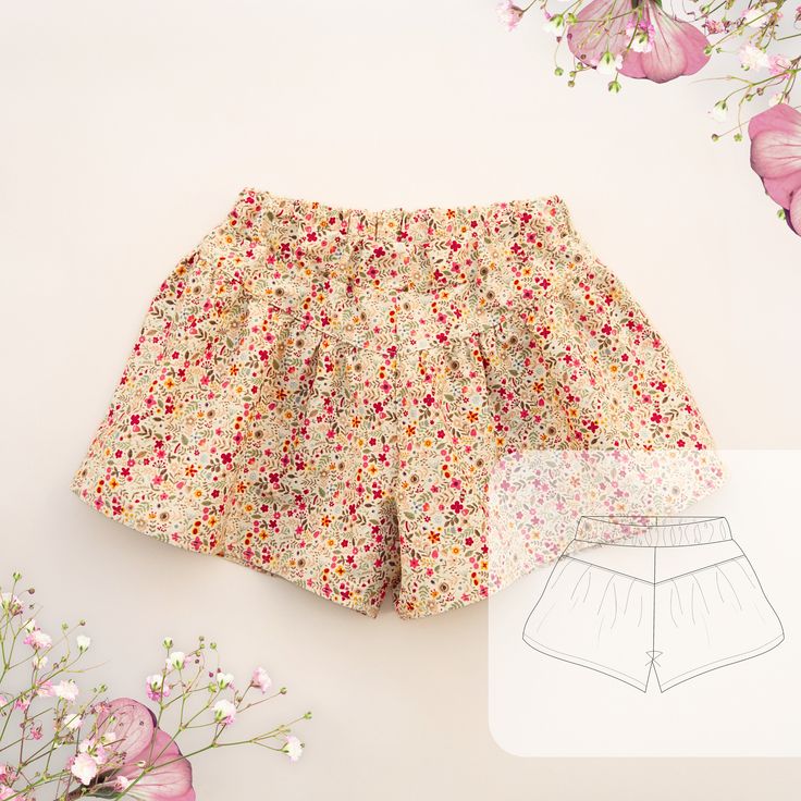 a pair of shorts with flowers on them next to a flowery paper cutout