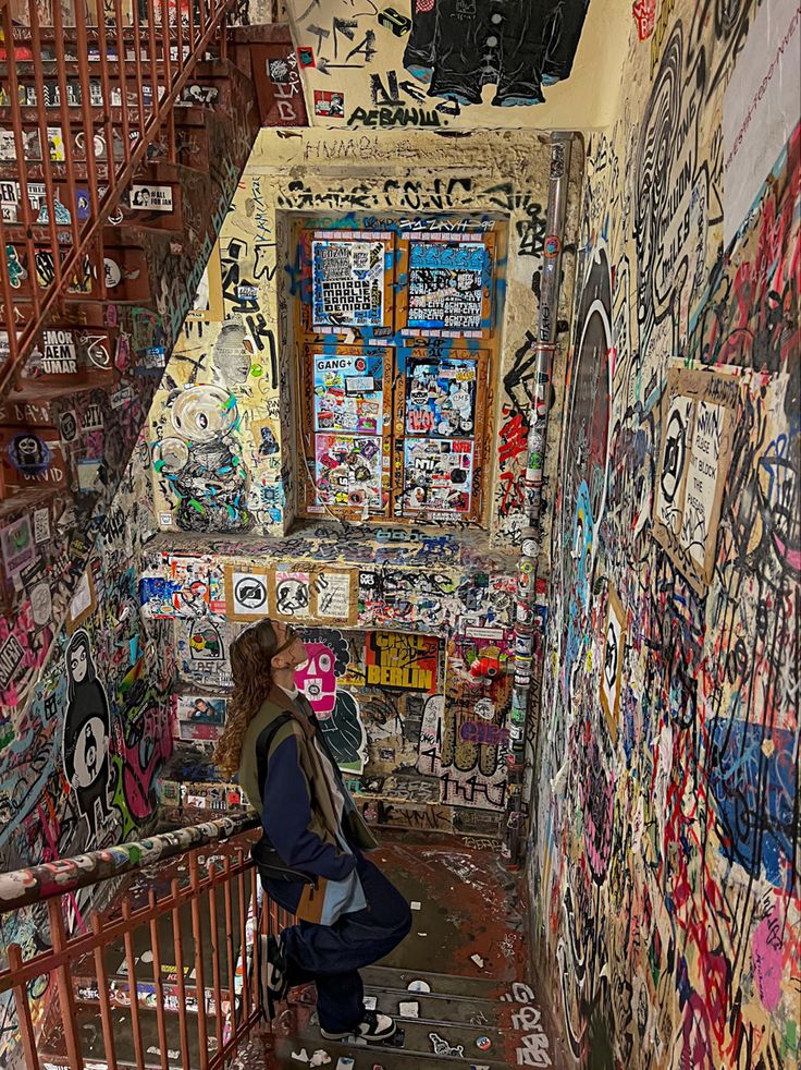 there is a woman that is walking up the stairs covered in graffiti and stickers