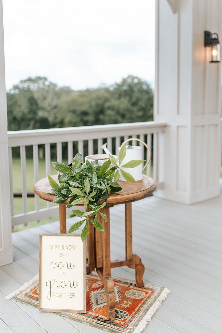 a small table with a sign on it and a potted plant