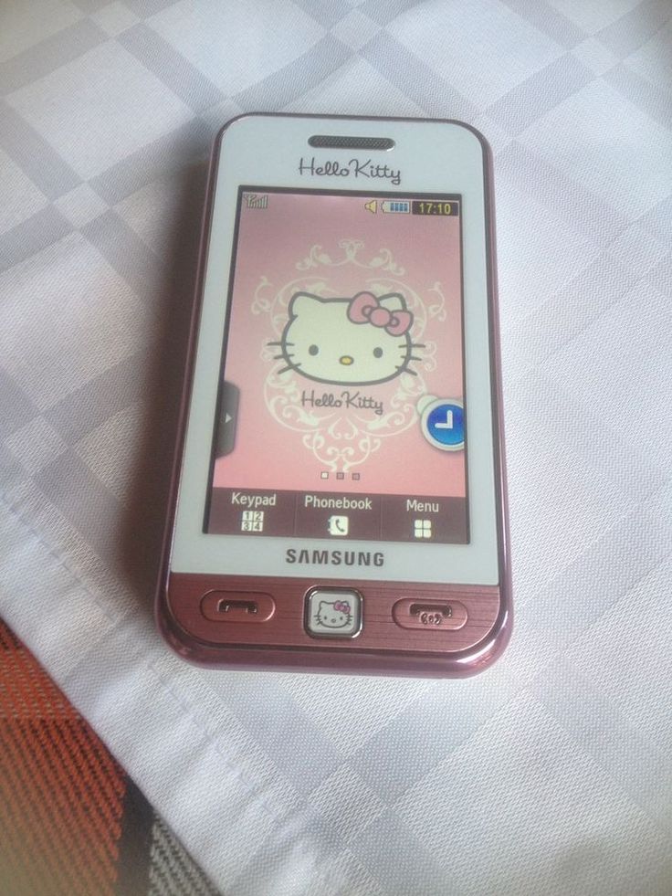 a pink cell phone sitting on top of a white table cloth covered bedding with an hello kitty theme