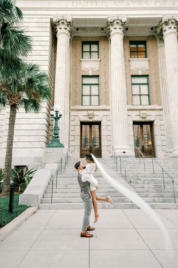 a bride and groom kissing in front of the stately building