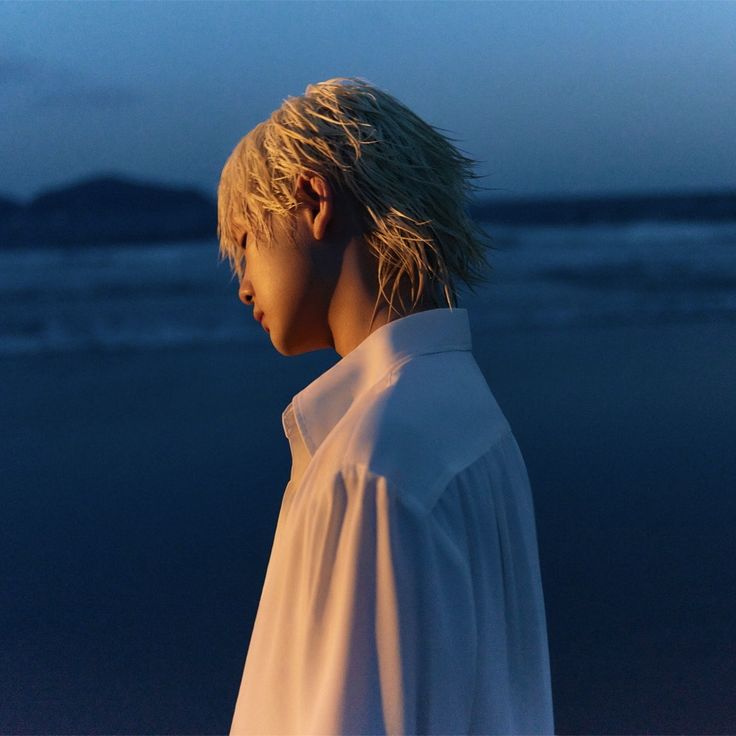 a person with blonde hair standing on the beach