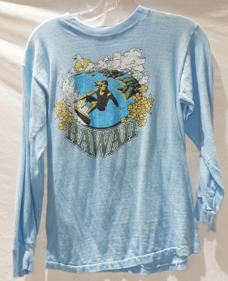 VINTAGE PRODUCTIONS Presents 1970's Hawaii Surfer / Surfing Long Sleeve T-shirt. Light blue body. Has a screen printed image of a surfer riding waves on side of the islands. Marked a size medium. Has been used and worn but still in good shape. Some minor discoloring in pits. Shoulder to shoulder: 17  inches armpit to armpit: 17 inches sleeve length: 18  inches Bottom of collar to hem: 22 inches We only ship via Priority mail in in the US and out side the US it is done only by Global / Internatio Retro Graphic Print Crew Neck Top, Retro Crew Neck Top With Graphic Print, Retro Long Sleeve Tops With Screen Print, Vintage Long Sleeve Relaxed Fit T-shirt, Vintage Crew Neck Shirt With Graphic Print, Retro Crew Neck Shirt With Vintage Print, Vintage Long Sleeve T-shirt With Letter Print, Retro Graphic Crew Neck Tee, Vintage Long Sleeve T-shirt With Screen Print