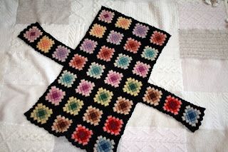 a black crocheted blanket with multicolored flowers on it