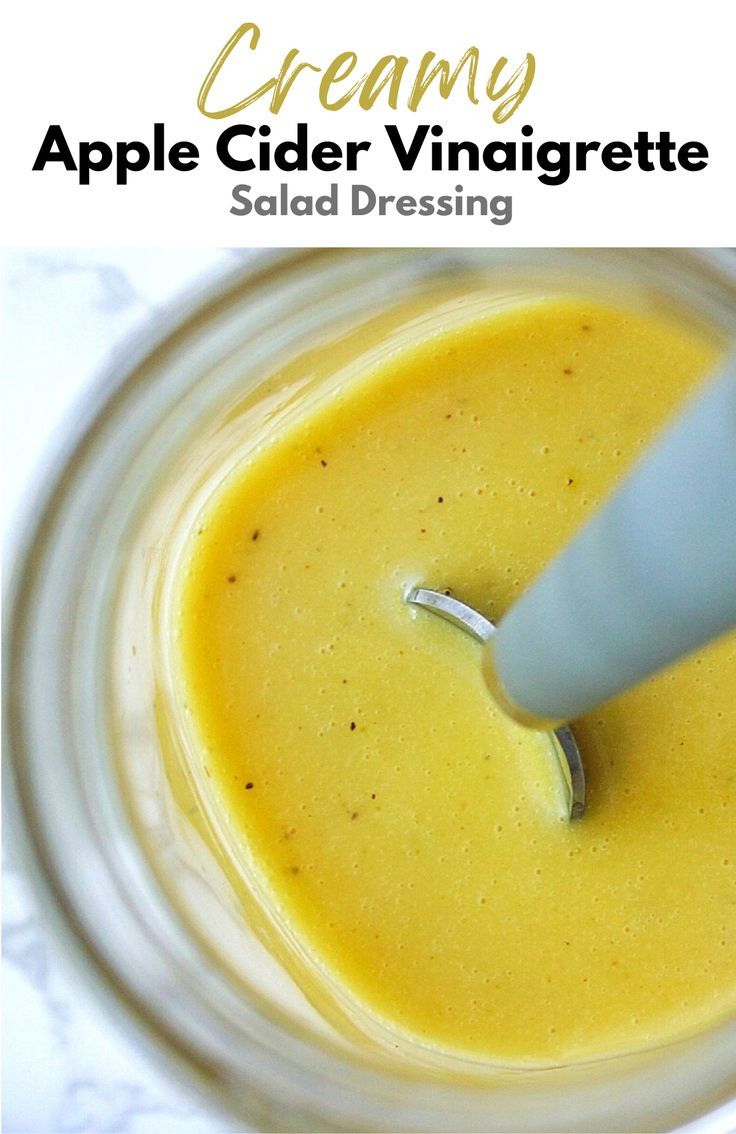 an apple cider vinaigrette is in a glass jar with a spoon