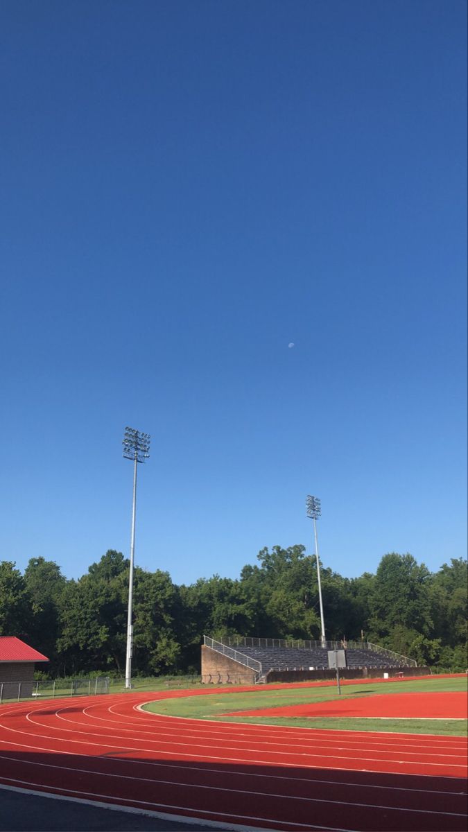 an empty baseball field with the sky in the background and trees on the other side