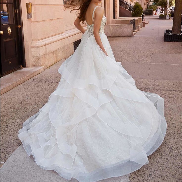 a woman is walking down the street wearing a wedding dress with ruffles on it