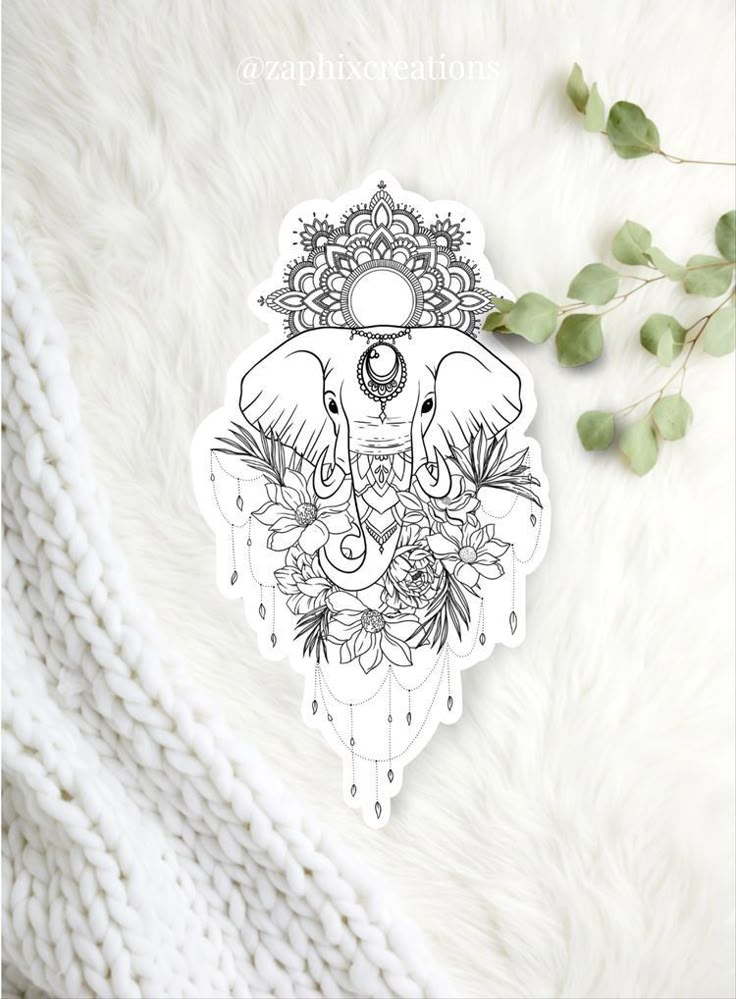 an elephant sticker sitting on top of a white blanket next to some leaves and flowers