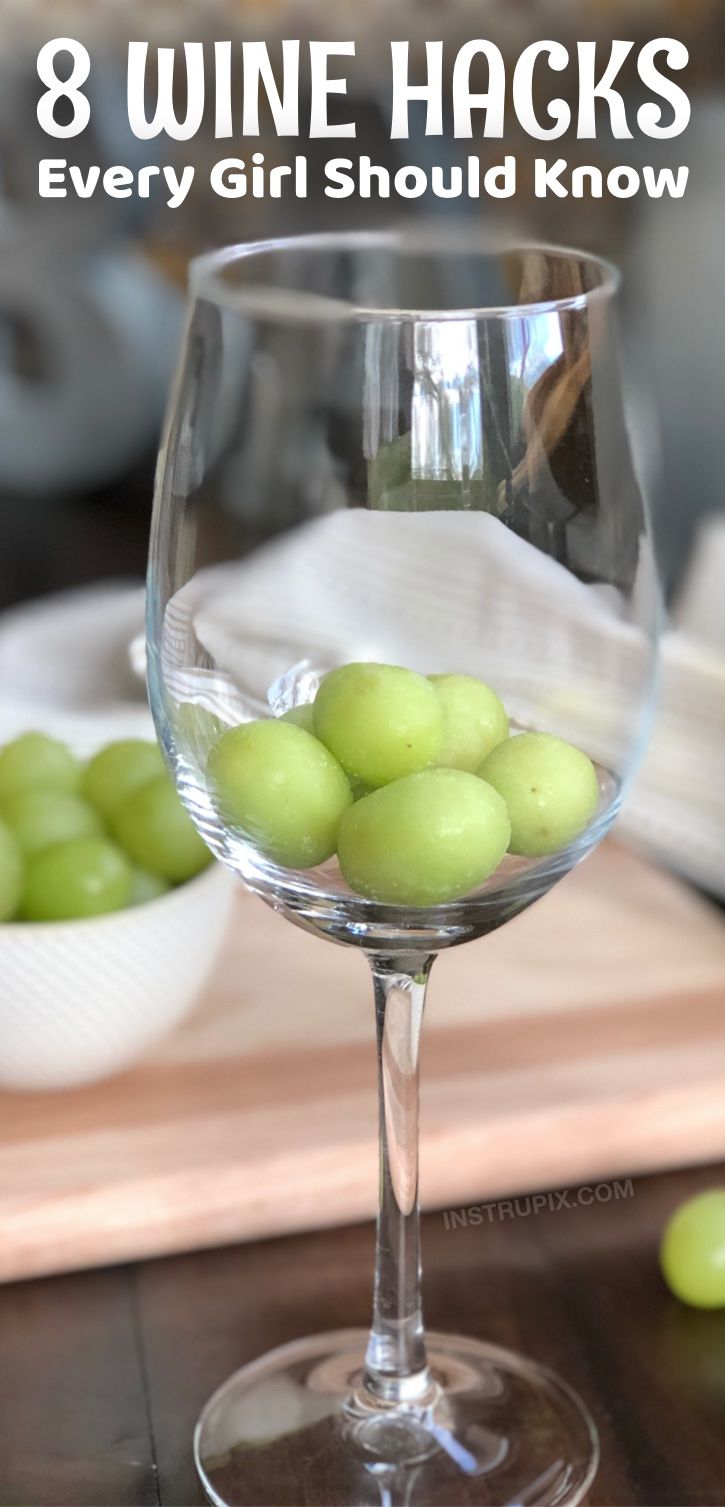 a wine glass filled with green grapes on top of a wooden table