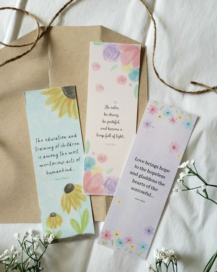 three bookmarks with flowers on them sitting next to some paper and twine string