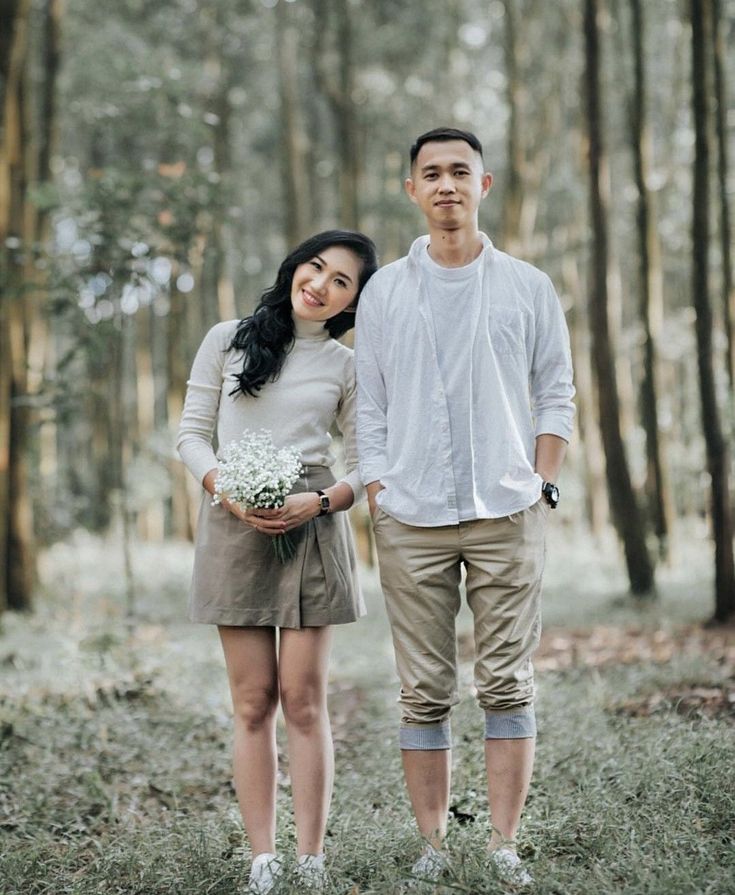 a man and woman standing next to each other in the woods