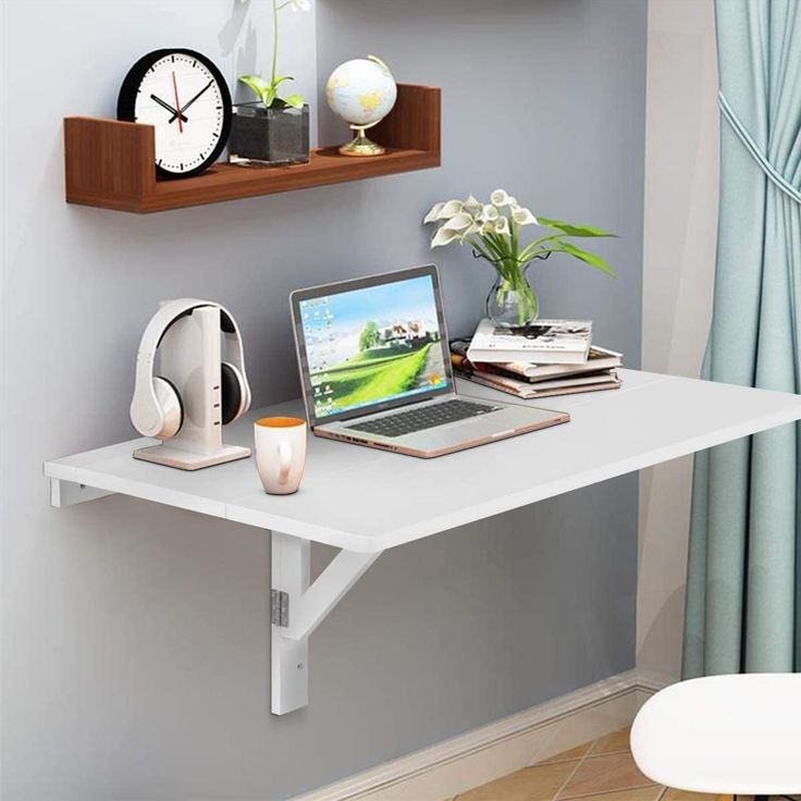 a laptop computer sitting on top of a white desk next to a clock and plant