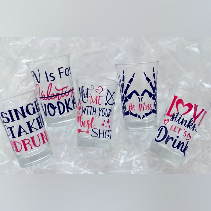 four shot glasses with different designs on them sitting in plastic wrapper next to each other