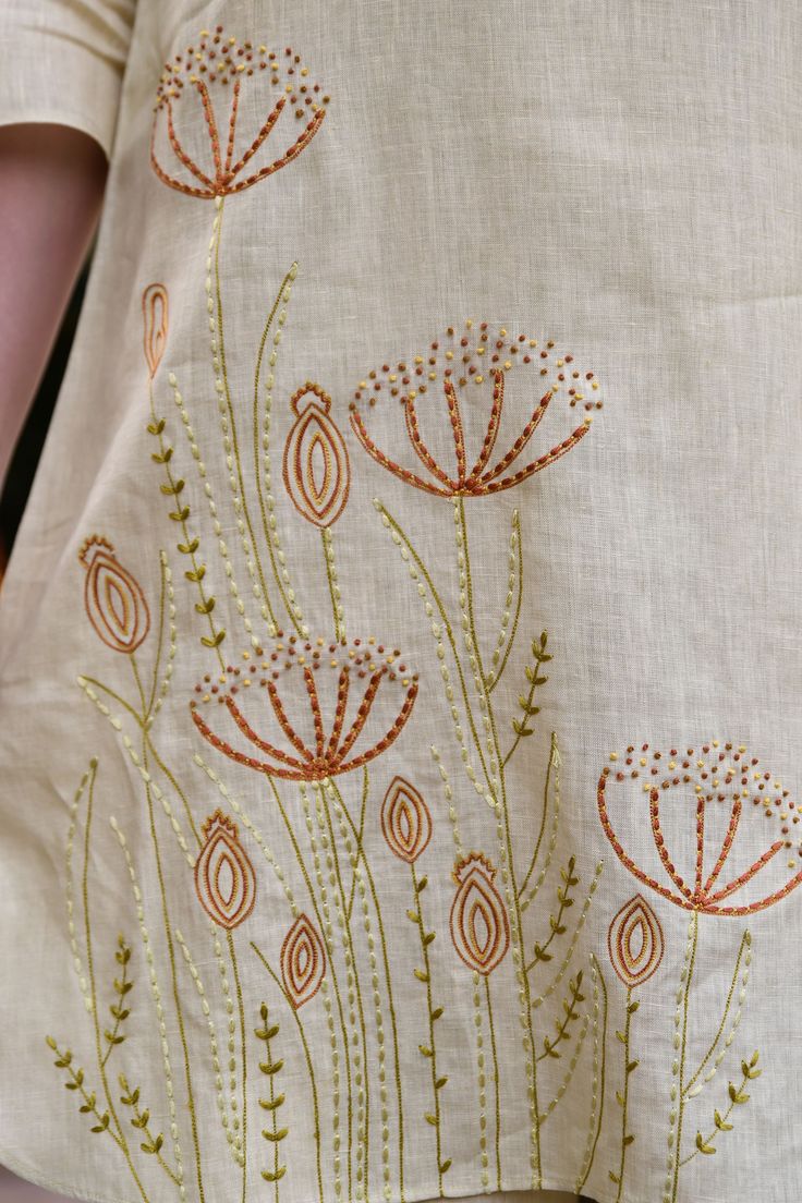 a woman is wearing an embroidered shirt with flowers on it